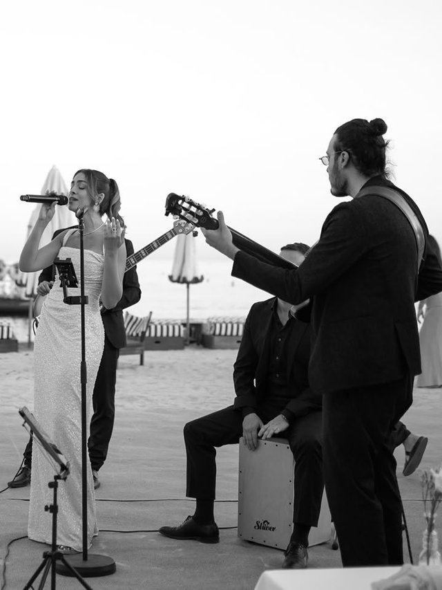 Mayssa singing with her band on the beach